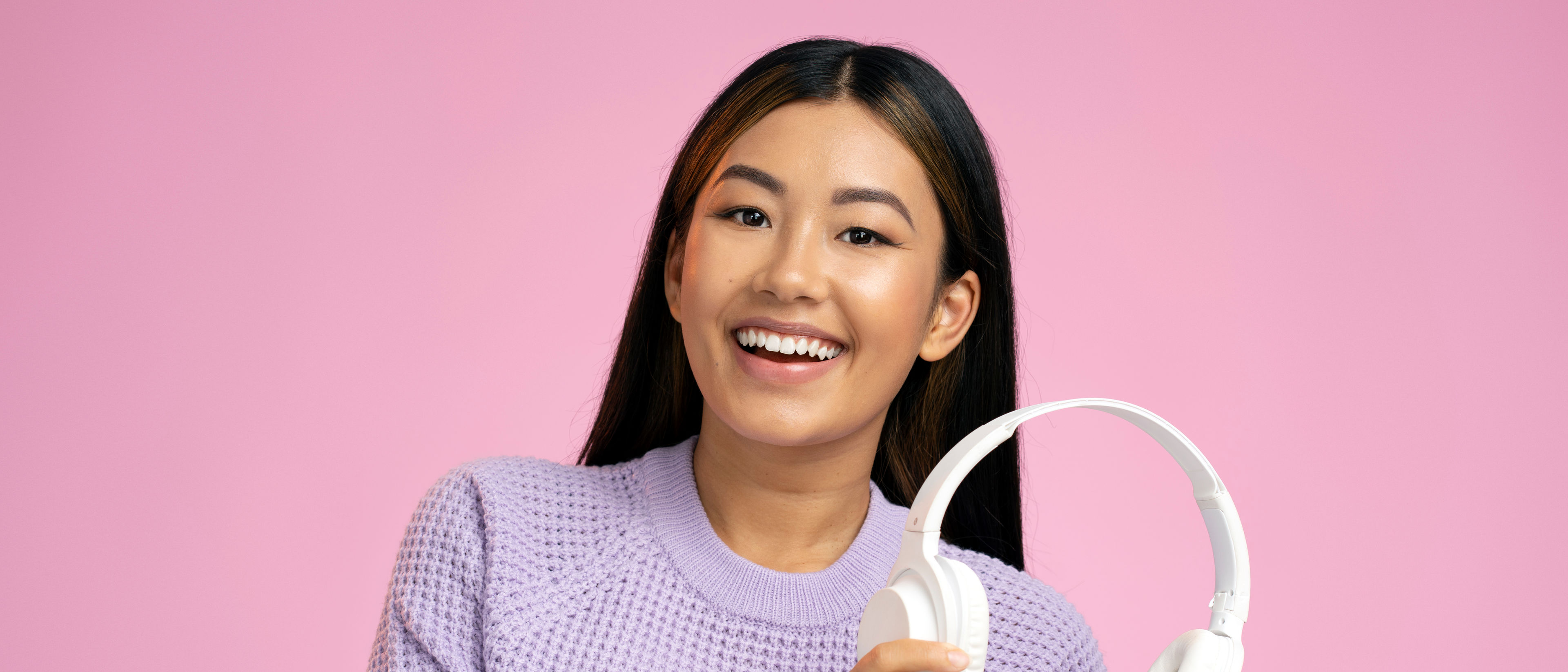 cheerful woman holding wireless headphones