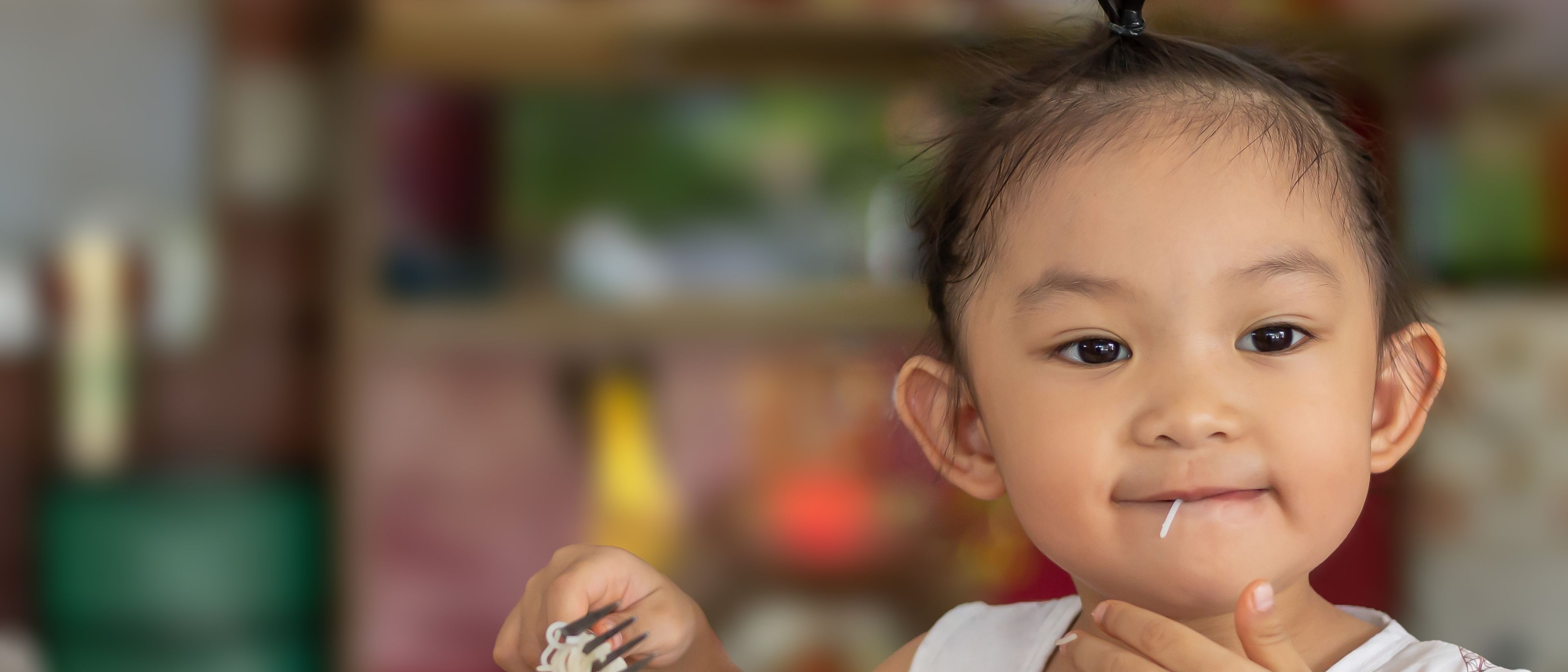 Happy girl eating noodles